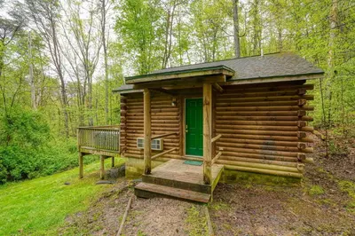 a log cabin with a green door in the woods at Blue Rose Cabins - Big Woody Cabin in Logan