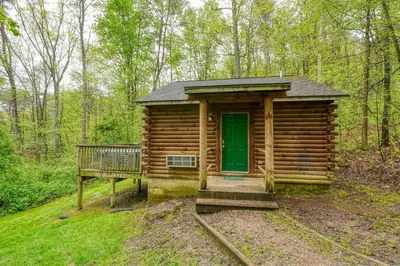 a log cabin with a green door in the woods at Blue Rose Cabins - Big Woody Cabin in Logan