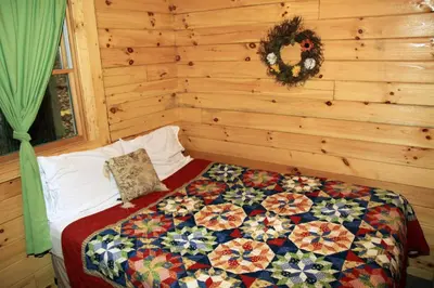 a bedroom with a bed with a quilt on it at Blue Rose Cabins - Big Woody Cabin in Logan