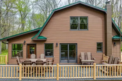 a house with a deck with chairs and a table at Family-Friendly Milton Home on 14 Acres with Hot Tub in Milton