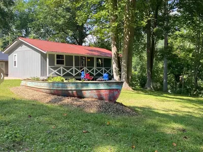 a boat sitting in the grass in front of a house at White Oak Cabin in Argillite