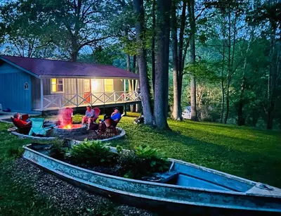 a group of people sitting around a fire pit in front of a house at White Oak Cabin in Argillite