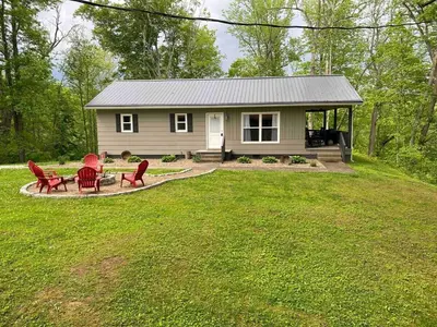 a small house with red chairs and a patio at Hickory House Cabin in Ashley
