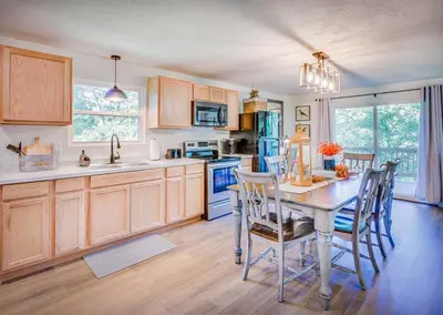 a kitchen with wooden cabinets and a table with chairs at Hickory House Cabin in Ashley