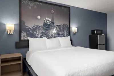 a bedroom with a white bed and a picture on the wall at Super 8 by Wyndham Fort Wayne in Fort Wayne