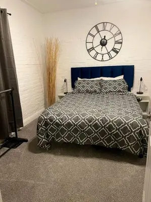 a bedroom with a bed with a clock on the wall at Charming Urban Retreat - Near UC, Med Centers, OTR in Cincinnati