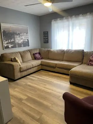 a living room with a large couch and a wooden floor at Charming Urban Retreat - Near UC, Med Centers, OTR in Cincinnati