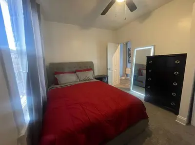 a bedroom with a red bed and a dresser at Charming Urban Retreat - Near UC, Med Centers, OTR in Cincinnati