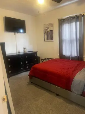 a bedroom with a bed and a dresser with a red blanket at Charming Urban Retreat - Near UC, Med Centers, OTR in Cincinnati