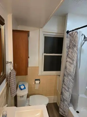 a bathroom with a toilet and a sink and a window at Unit 2 at Oilgate at Oakdale in Akron