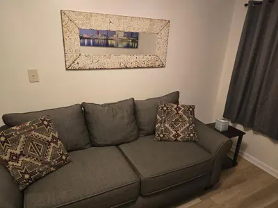 a living room with a gray couch with pillows at Unit 2 at Oilgate at Oakdale in Akron