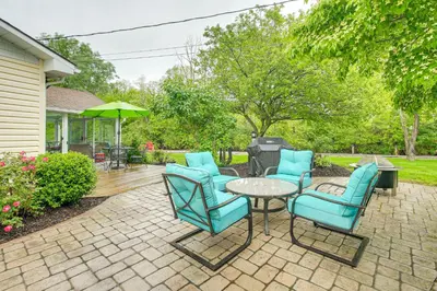 a patio with blue chairs and a table and umbrella at Thornville Home with Boat Dock On the Lake! in Hebron