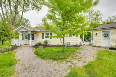 a small yellow house with a tree in the yard at Thornville Home with Boat Dock On the Lake! in Hebron