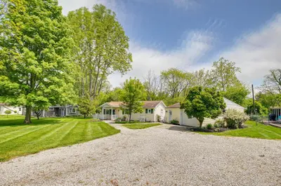 a home with a gravel driveway and trees at Thornville Home with Boat Dock On the Lake! in Hebron