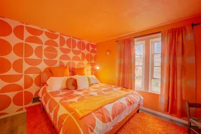 a bedroom with a bed with orange walls and a window at Retro 1970's Rollercoaster House 5 Mins from Cedar Point in Sandusky