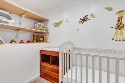 a white nursery with a crib andanimal stickers on the wall at Four-Bedroom House in Lapel