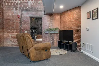 a living room with a chair and a television at Unique and Charming Downtown Apt in Newark