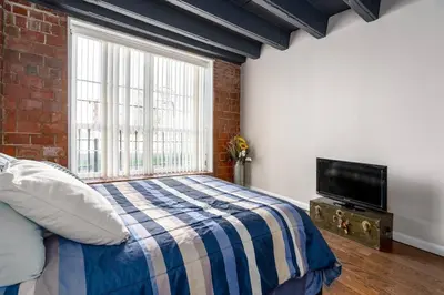 a bedroom with a bed and a tv and a brick wall at Unique and Charming Downtown Apt in Newark