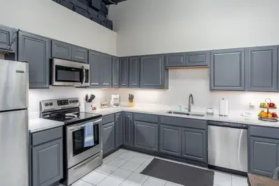 a kitchen with dark blue cabinets and stainless steel appliances at Unique and Charming Downtown Apt in Newark