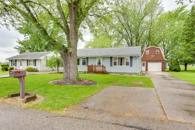 a house with a tree in the front yard at Port Clinton Home Hot Tub, Steps to Portage River in Port Clinton