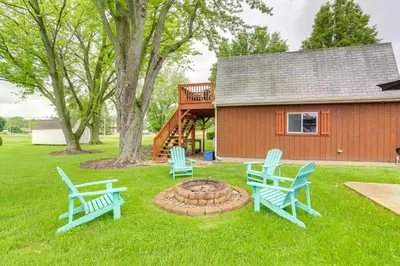 three blue chairs sitting in the grass in front of a cabin at Port Clinton Home Hot Tub, Steps to Portage River in Port Clinton