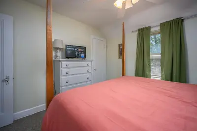a bedroom with a bed and a dresser with a television at Rachel's Private Hideaway with king bed, kitchen, laundry, parking and big yard in Toledo