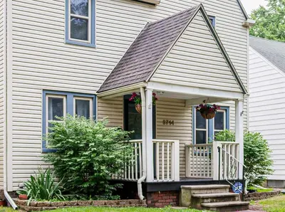 a white house with a porch with flowers on it at Rachel's Private Hideaway with king bed, kitchen, laundry, parking and big yard in Toledo