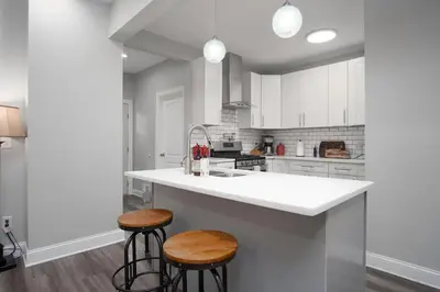 a kitchen with a white counter and two stools at Beautiful 4 Bedroom House Near Downtown Columbus with Garage Parking and Backyard in Columbus