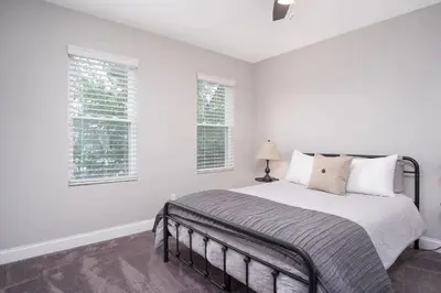 a white bedroom with a bed and two windows at Beautiful 4 Bedroom House Near Downtown Columbus with Garage Parking and Backyard in Columbus
