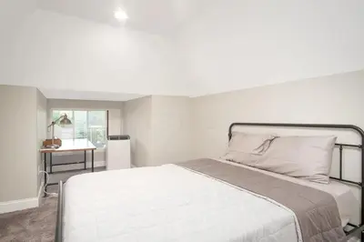 a white bedroom with a bed and a table at Beautiful 4 Bedroom House Near Downtown Columbus with Garage Parking and Backyard in Columbus