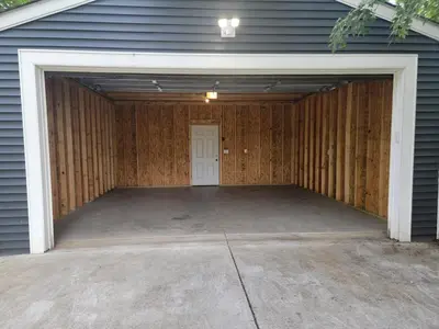 an empty garage with a white door and a driveway at Beautiful 4 Bedroom House Near Downtown Columbus with Garage Parking and Backyard in Columbus