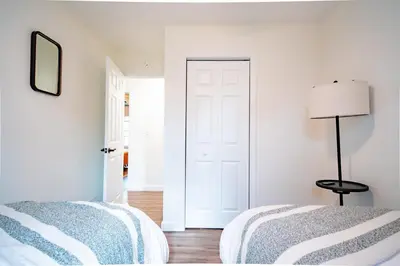 a white bedroom with two beds and a lamp at Lake Erie BreezeYour Restful Vermilion 3BR Vacation Home close to Cedar Point in Vermilion