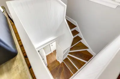 a spiral staircase in a house with white walls and wood floors at Cincinnati Apartment 1 Mi to Hyde Park Square! in Cincinnati