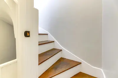 a staircase in a house with white walls and wooden steps at Cincinnati Apartment 1 Mi to Hyde Park Square! in Cincinnati