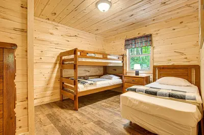 a bedroom with two bunk beds in a log cabin at Hike, Fish and More! Cozy Cabin in Hocking Hills in South Bloomingville