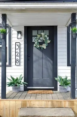 a black front door of a house with two potted plants at The Towpath Retreat-A Cozy Farmhouse Stay in Canal Fulton