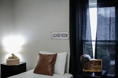 a bedroom with a couch and a window with a sign at Touchdown Bungalow-Charming HOF Village Home in Canton