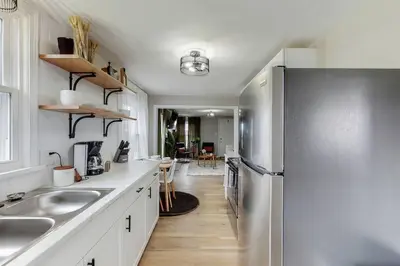 a kitchen with a stainless steel refrigerator and white cabinets at Touchdown Bungalow-Charming HOF Village Home in Canton