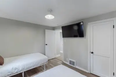 a white room with a bed and a flat screen tv at Touchdown Bungalow-Charming HOF Village Home in Canton