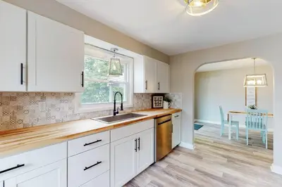 a kitchen with white cabinets and a sink and a table at Football Hall of Fame Hideaway-Cozy and Convenient in Canton