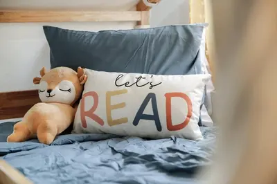 a teddy bear sitting on a bed with a lets read pillow at The Huddle House-HOF Home Made for Families in Canton