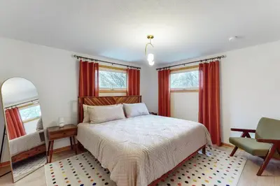 a bedroom with a bed and a chair and windows at Gridiron Getaway-Where Families and Fans Unite in Canton