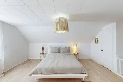 a white bedroom with a bed and a chandelier at End Zone Escape-Light and Bright HOF Village Home in Canton