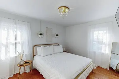 a white bedroom with a bed and a chandelier at End Zone Escape-Light and Bright HOF Village Home in Canton
