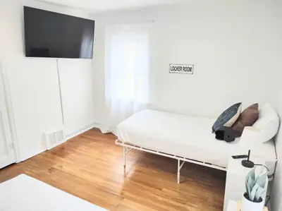 a white room with a bed and a flat screen tv at End Zone Escape-Light and Bright HOF Village Home in Canton