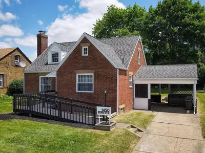 a brick house with a for sale sign in front of it at Home Champions-HOF Village Comfort in Canton