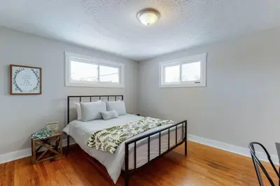 a bedroom with a bed with white walls and two windows at Steps to the HOF-Football Fans Dream Stay in Canton