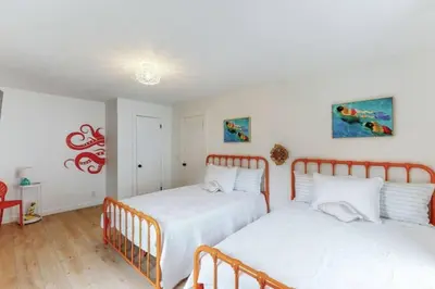 two beds in a bedroom with white walls and wood floors at The Playmakers Funhouse-HOF Village in Canton
