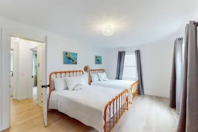 two beds in a bedroom with white walls and wood floors at The Playmakers Funhouse-HOF Village in Canton