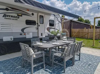 a table and chairs and a caravan with a trailer at Wildflower Wanderlust-Glamping st 1885 Farms in Navarre